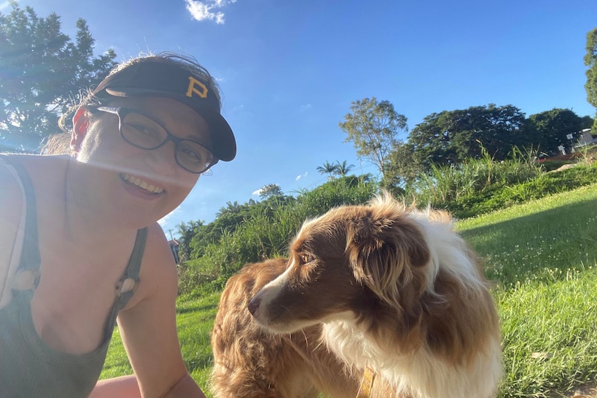 A woman in glasses and a cap with a chocolate border collie.