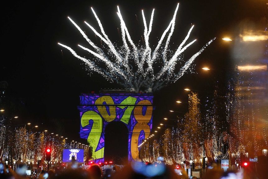 Paris' Arc de Triomphe has '2018' projected onto its arches as fireworks explode behind it.