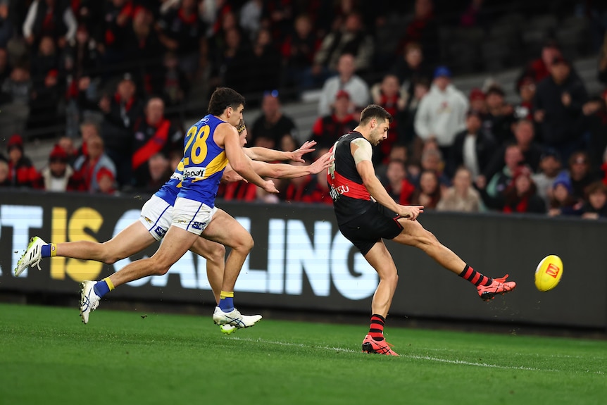 Kyle Langford gets a kick away as two Eagles players chase him from behind