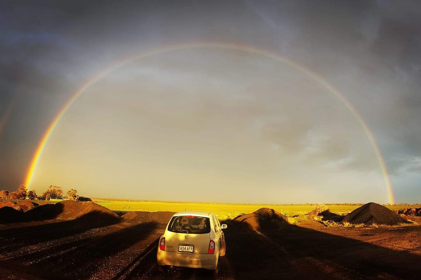 A rainbow over a car and field
