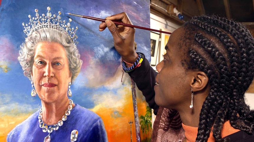 A woman leans in close to a portrait of Queen Elizabeth II holding a paintbrush with blue paint on it.