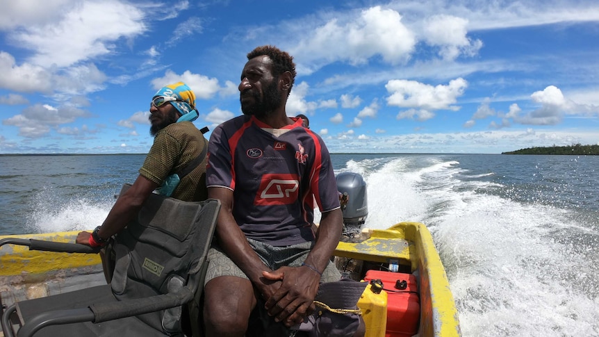 Two Papua New Guinean men sitting on a boat heading out to the sea.