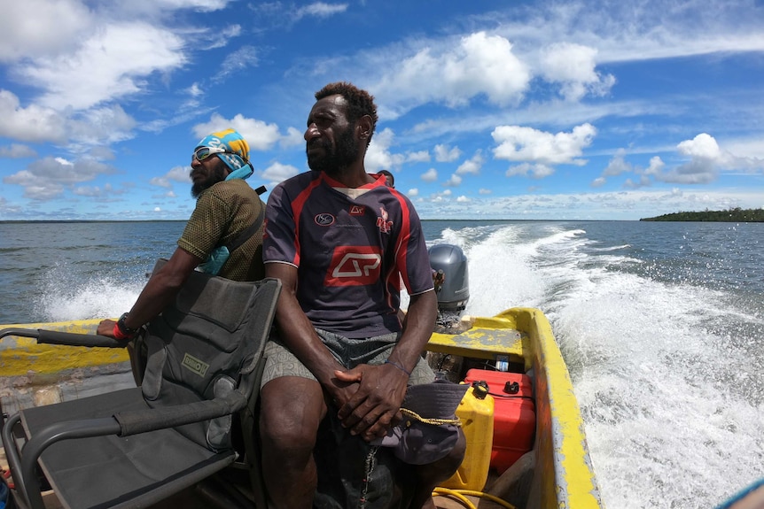 Two Papua New Guinean men sitting on a boat heading out to the sea.