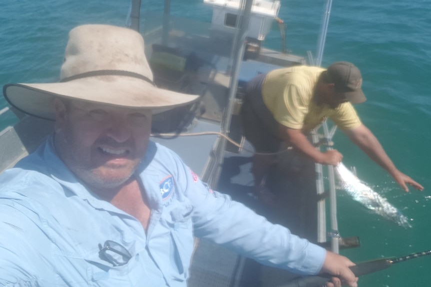 A photo of two fishermen on board a boat in broad daylight.