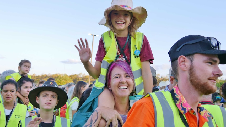 young girl and mum in high vis vests with young girl on shoulders.