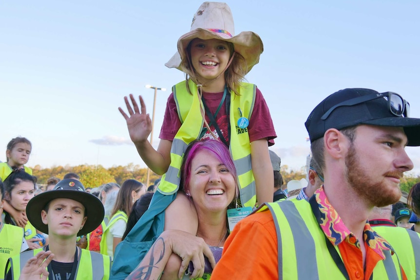 young girl and mum in high vis vests with young girl on shoulders.