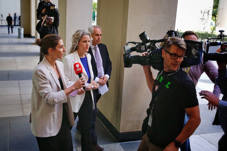Clare O'Neil and Andrew Giles are followed by media after leaving a press conference at parliament house
