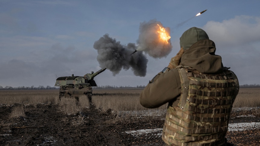 Ukrainian soldier stands as he watches a launch rocket launch take off into the sky.