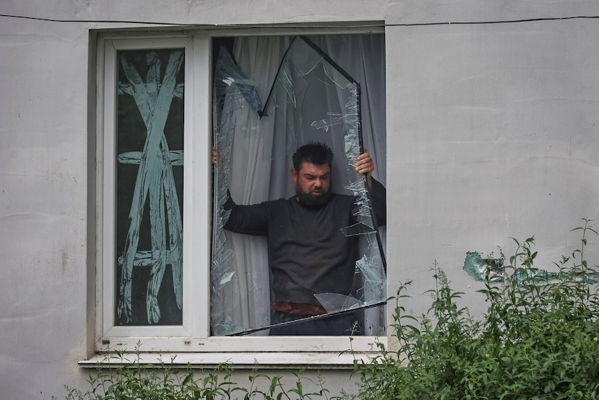 A man reoved a shattered window pane from his window 