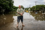 A man standing in front of flood waters in Lismore.