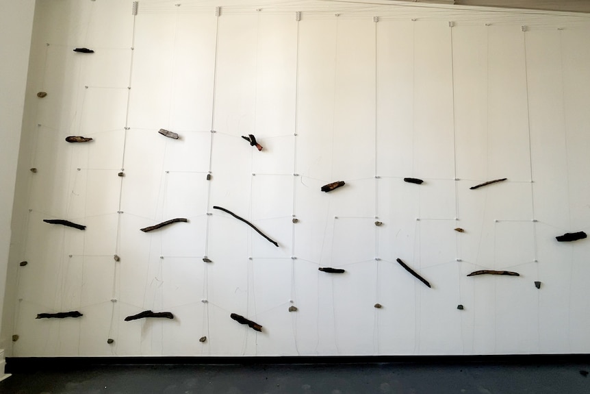 Pieces of charred wood and rock on a wall in an art exhibit