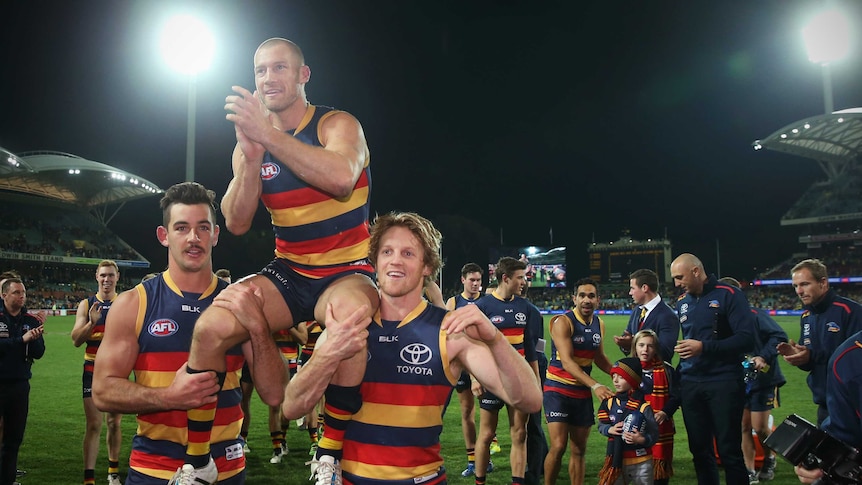Adelaide's Scott Thompson is chaired off Adelaide Oval by teammates Taylor Walker and Rory Sloane.