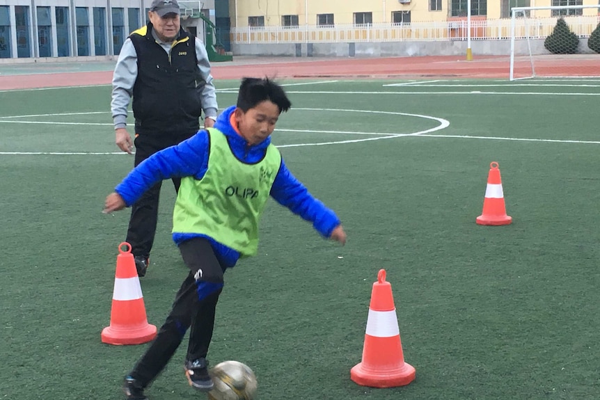 Aspiring Chinese footballer Gao Baosen, 12, steers a ball around witches' hats at training.