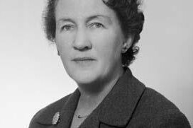 A black and white portrait of a woman in a suit jacket.