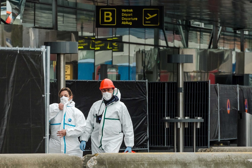 Forensic officers walk in front of the damaged Zaventem Airport terminal in Brussels.