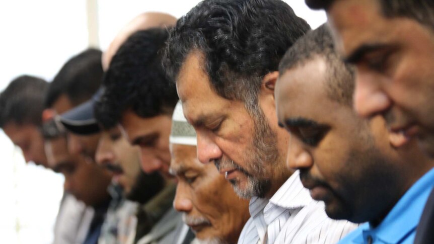 Men bow their head in prayer at the Parramatta Mosque