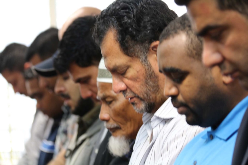 Men bow their head in prayer at the Parramatta Mosque