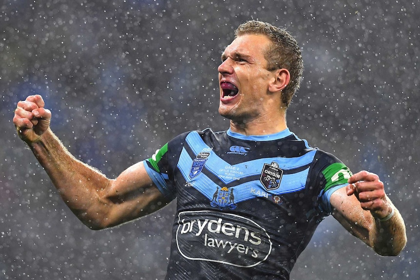 NSW Blues player Tom Trbojevic's biceps bulge as he screams into a rainy night sky during State Of Origin Game Two.