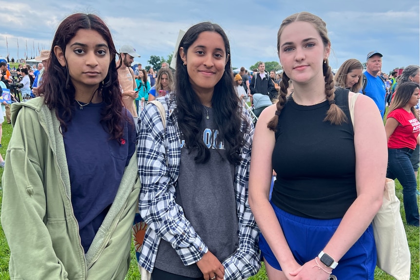 Simrin Arora, Siona Arora and Mary Miller stand together in front of a crowd of people at the March for Our Lives rally 