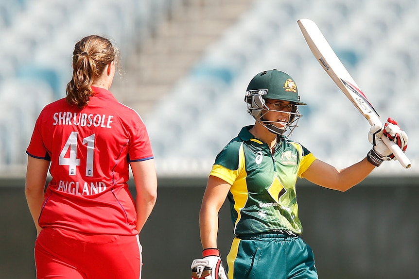 Nicole Bolton raises her bat to her teammates in the dugout after making 100 on debut