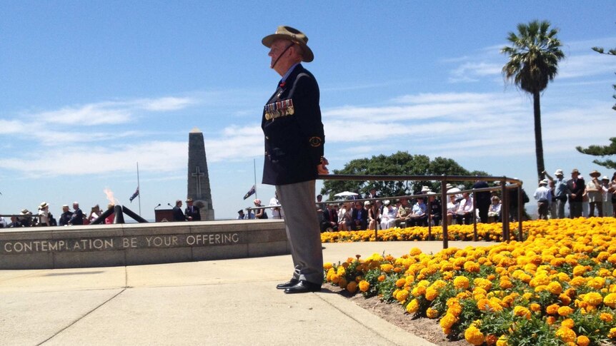 A former soldier wearing medals stands to attention at Kings Park War Memorial, Remembrance Day 2013.