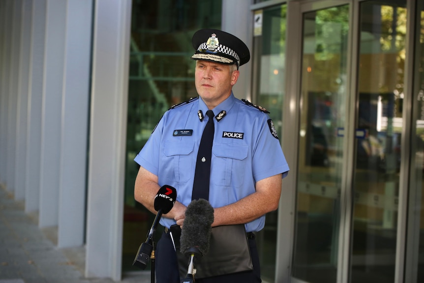 A wide shot of WA Police Commissioner Col Blanch standing in front of microphones outside ABC Perth.