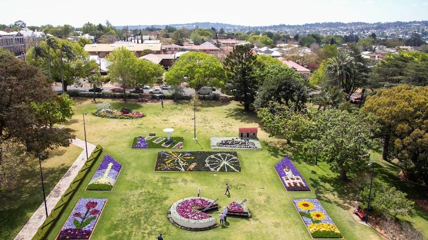 Aerial view of a green park with colourful flower beds.