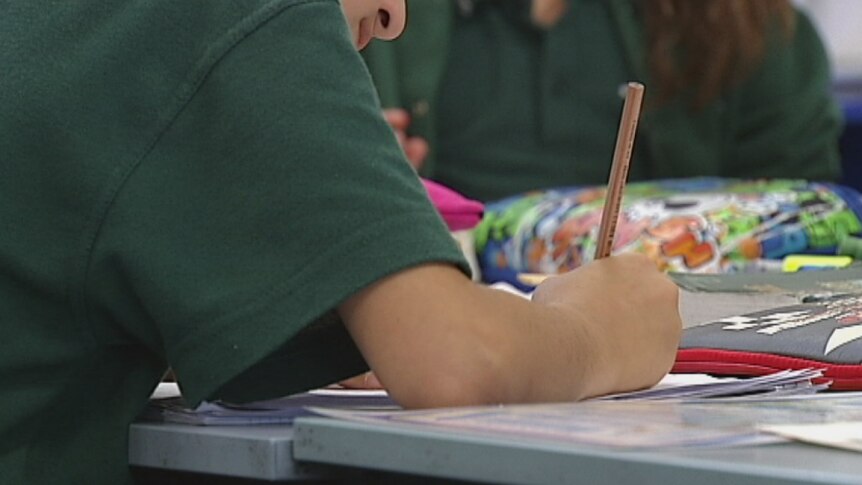 A photo of a students arm as they write in a book at school