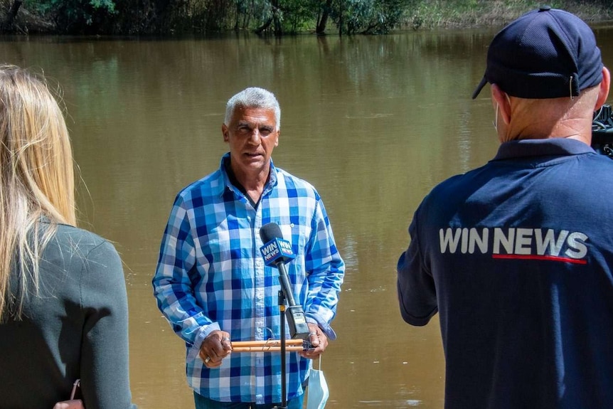 man is interviewed by reporter and cameraman