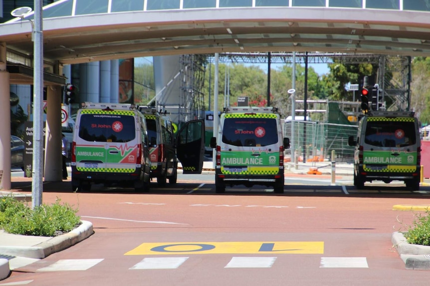 Three ambulances in an undercover shelter outside a hospital.