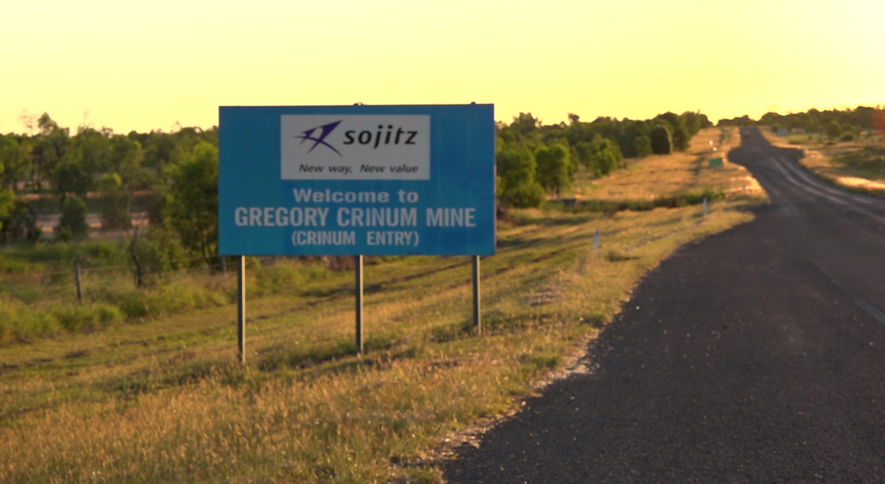 Blue sign with mine name on rural road with sunset