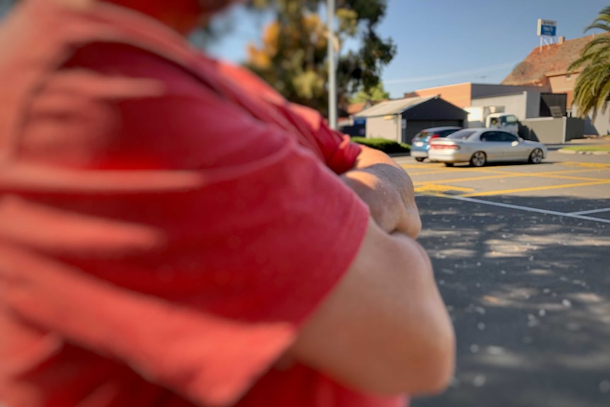 A man standing cross armed near a pokies venue.