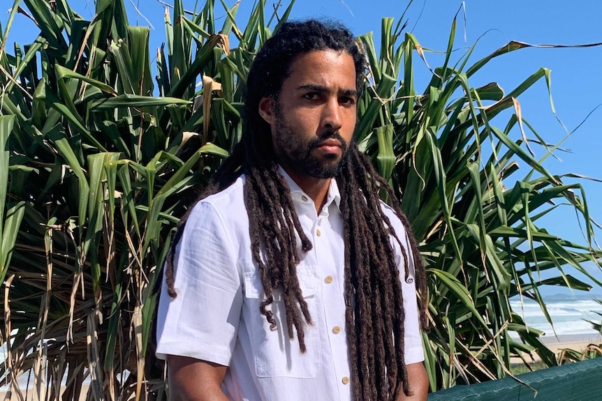 A man stands in front of a plant.