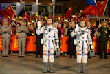 Chinese astronauts Jing Haipeng and Chen Dong wear their space suits and wave before the launch of Shenzhou