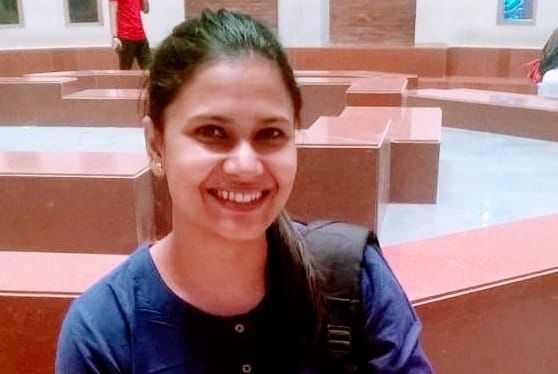 An Indian woman sits smiling at the camera. 