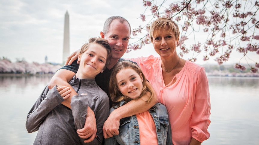 Family with arms around each other standing in front of Washington monument.