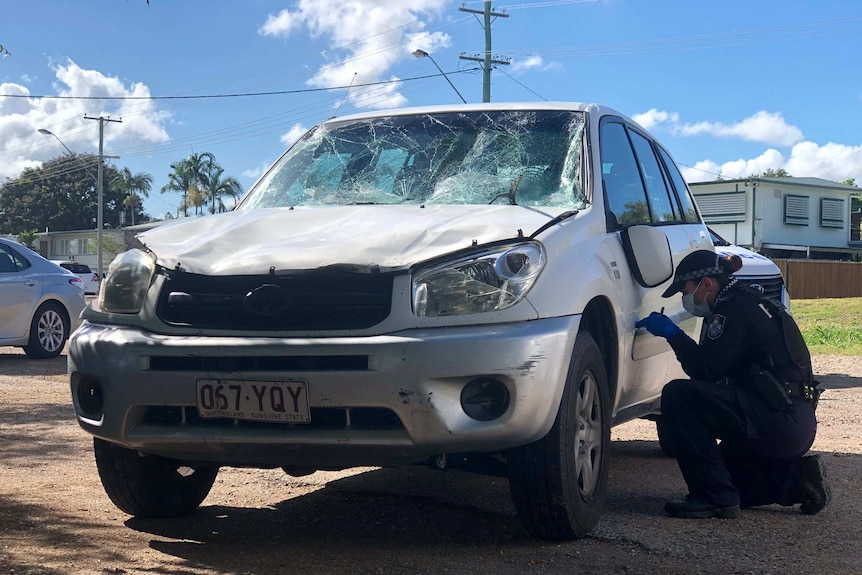 A police officer takes forensic evidence from the hatchback.