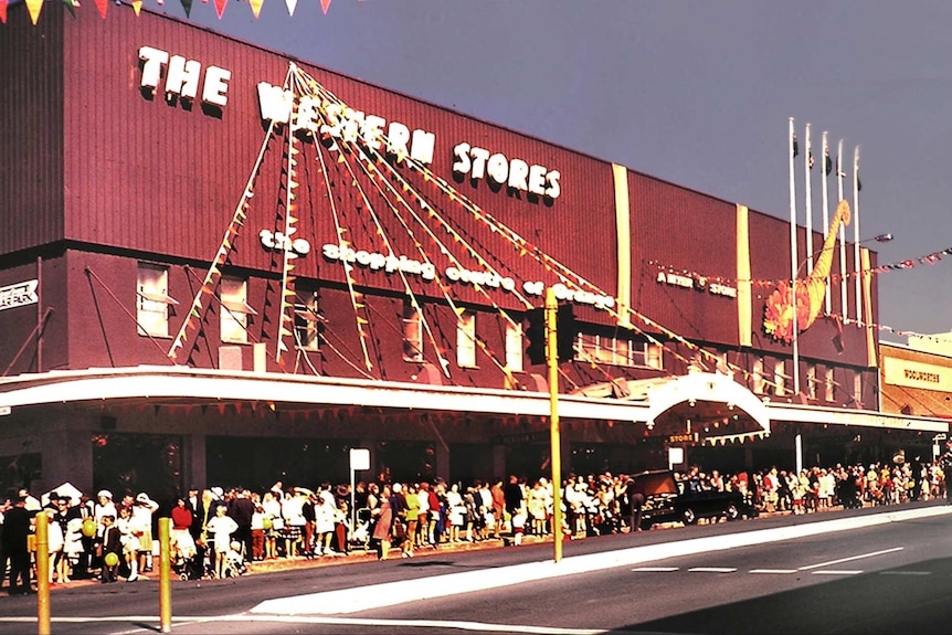 Colour photograph of a building saying the western stores, the shopping centre of Orange with crowds gathered outside