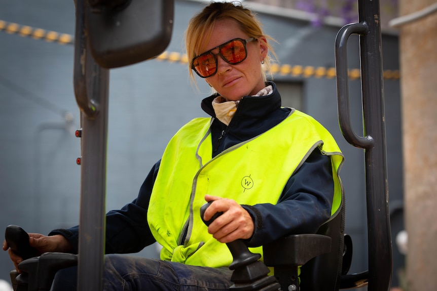 A young woman operating an excavator at a building site 