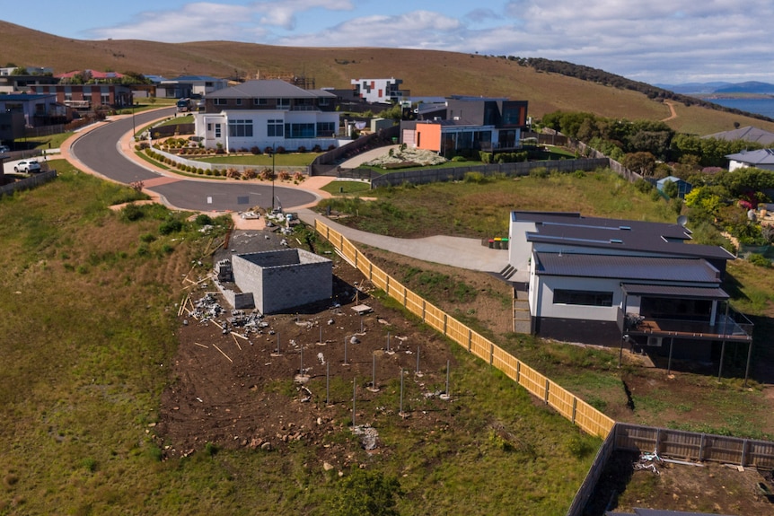 Aerial view of a house under construction surrounded by other houses.