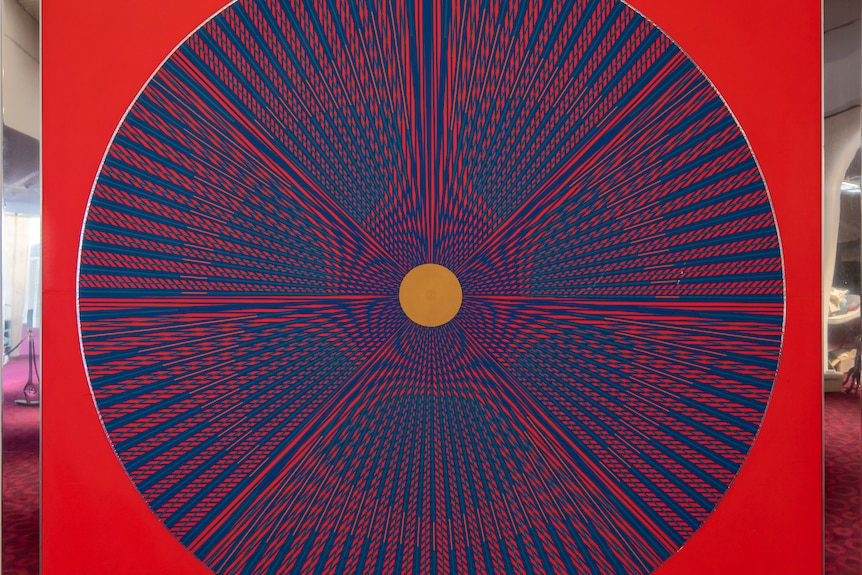 A blue spiral-like pattern on top of a red background set inside a square