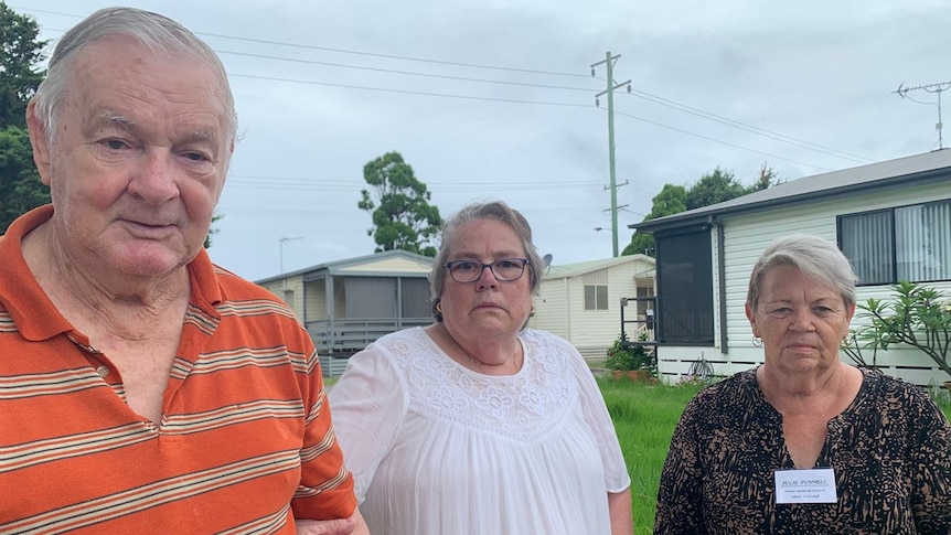 One man and two women standing in a caravan park looking concerned