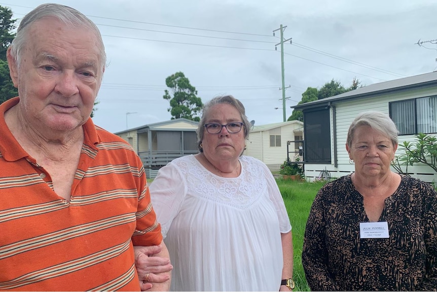 One man and two women standing in a caravan park looking concerned