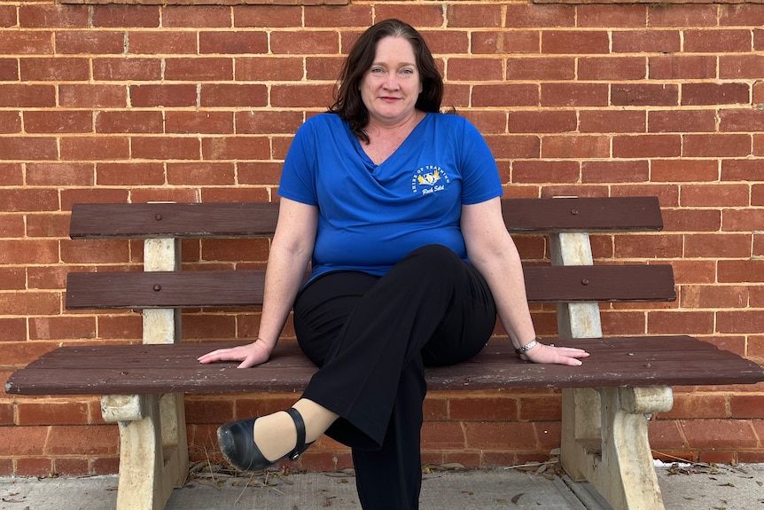 Trayning Shire CEO Leanne Parola sits on a bench in a blue top outside a post office.