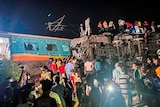 Rescuers scale the wreck of a train carriage tipped on its side.
