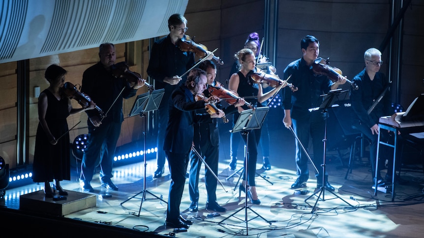 Members of the ACO string section perform on stage with a member of the Moog ensemble.