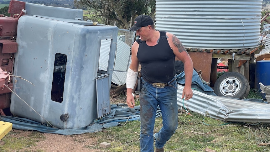 A man walks in front of a toppled trailer.