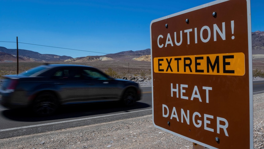 A car driving past a sign that reads: "Caution! Extreme heat danger".