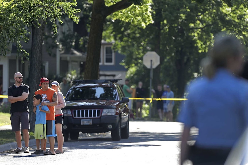 Police and residents are photographed on a suburban tree-lined street near a cordoned-off crime scene.