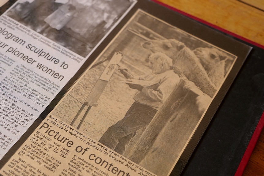 A newspaper clipping shows a man painting with his camels.